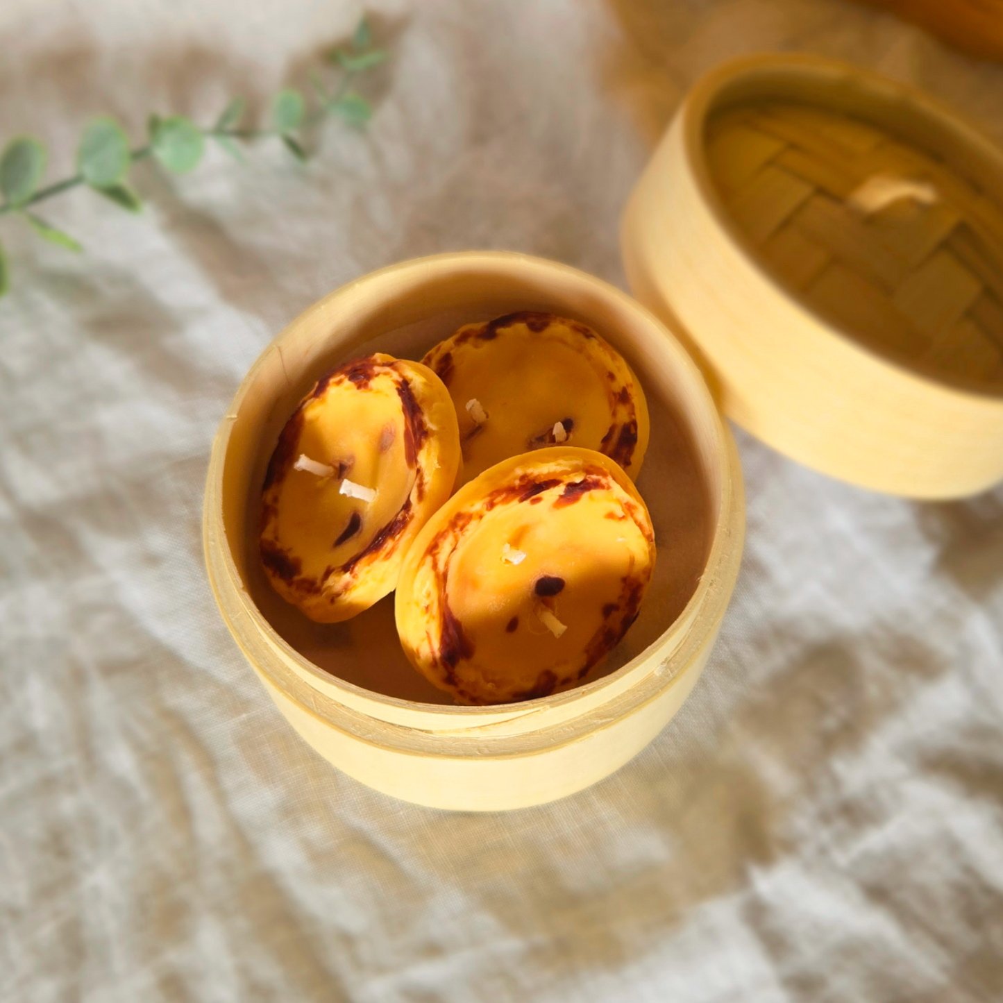 3 egg tart candles made of soy wax in a bamboo steamer by Candle Tales