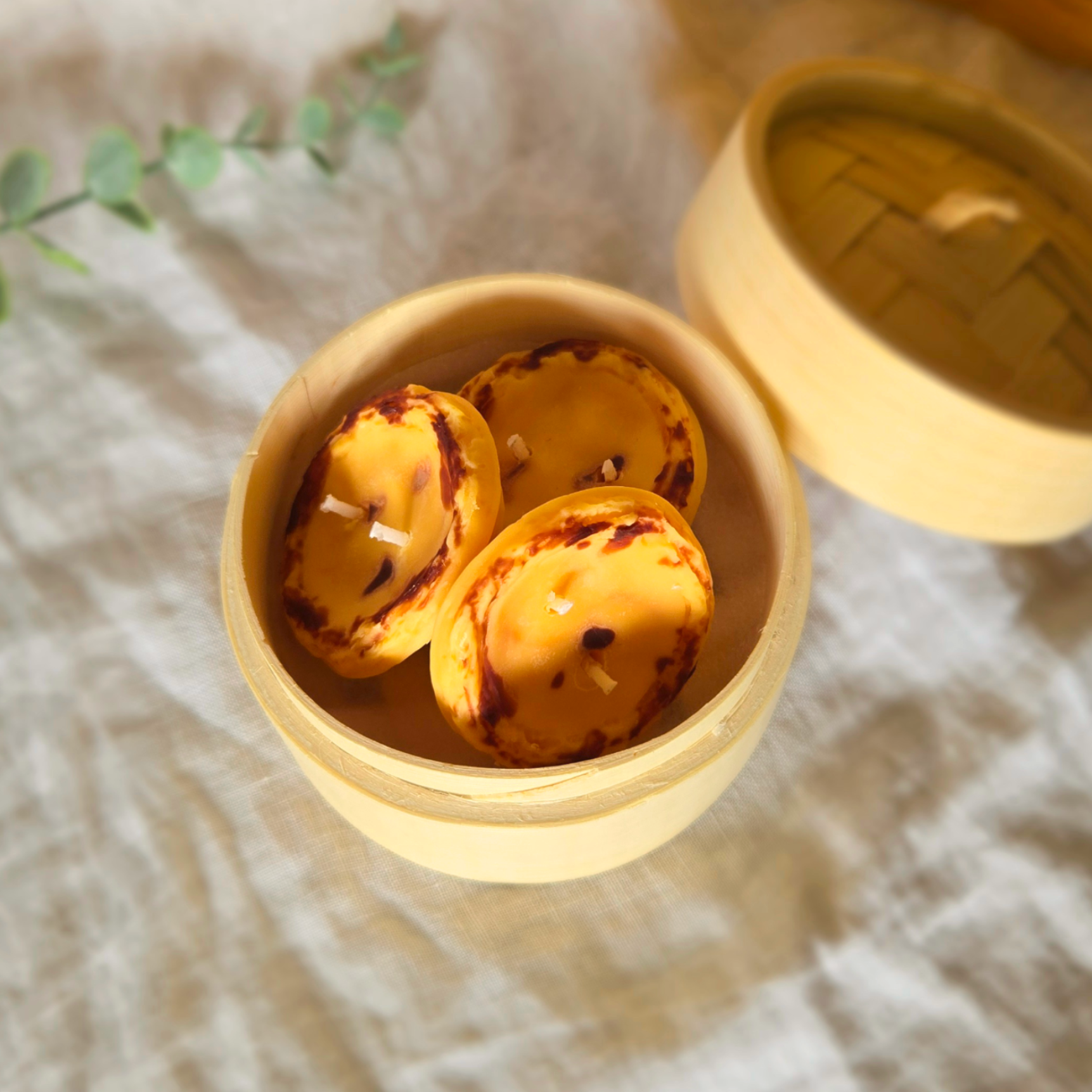 3 egg tart candles made of soy wax in a bamboo steamer by Candle Tales