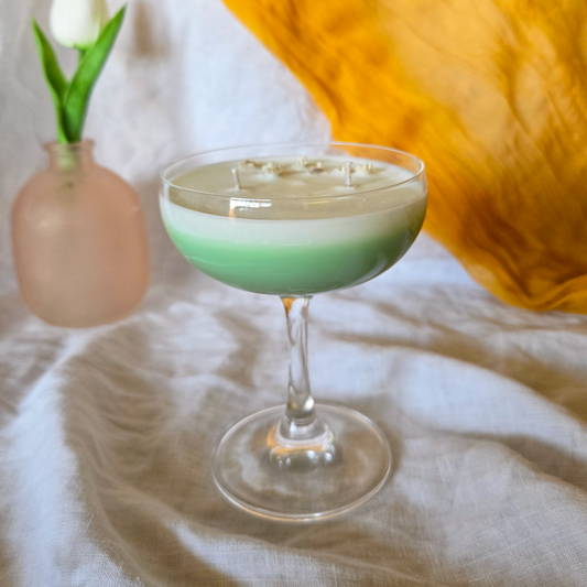 Spring fizz cocktail candle made of soy wax and dried flowers in a martini glass with a white tulip in the background